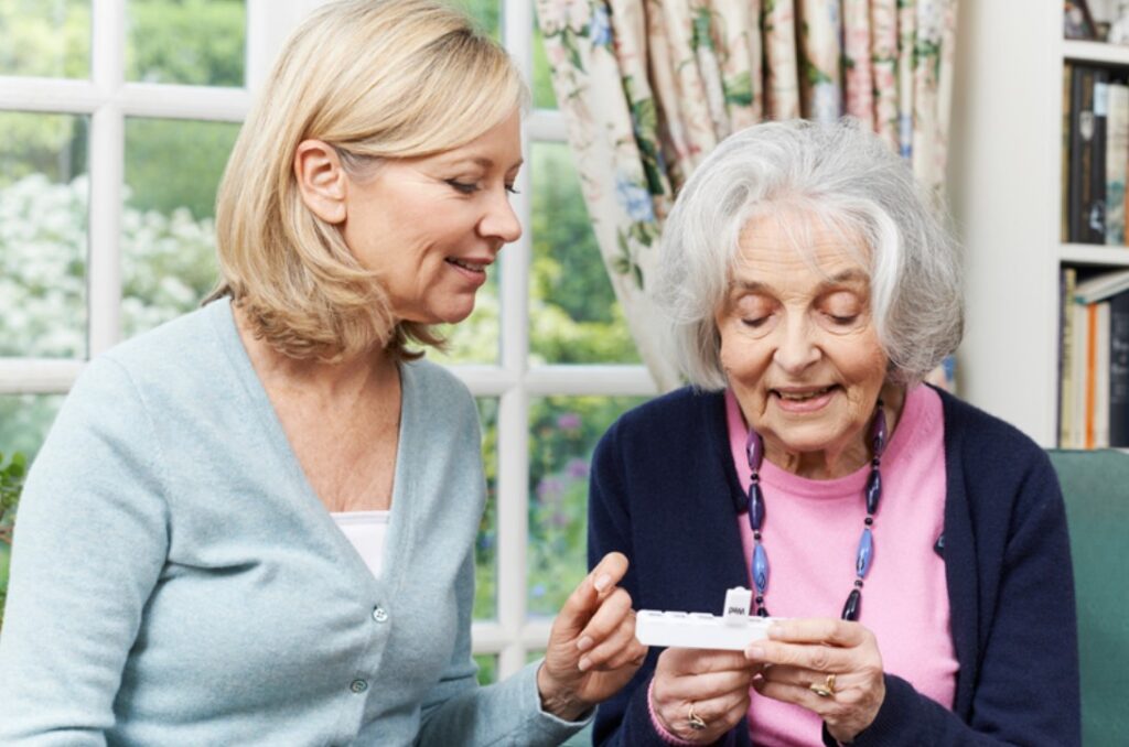 home health aide assisting an elderly patient by reminding them to take the medication in their daily pill organizer in new jersey or florida