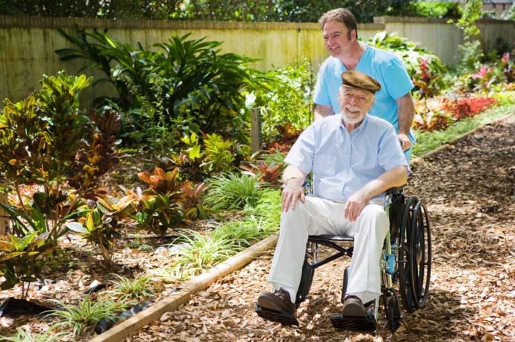 senior citizen outdoors in a wheelchair being assisted by a home health aide providing memory care for new jersey and florida patients at home